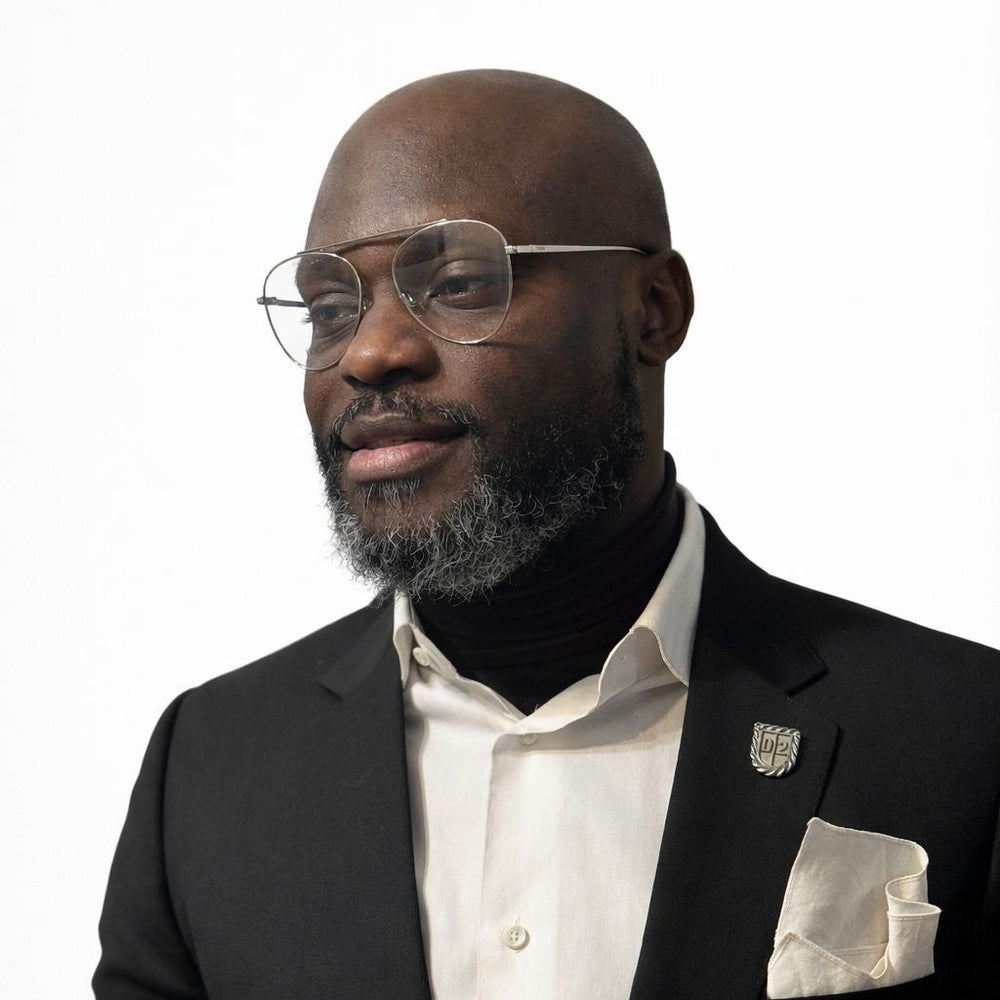 Man wearing a black suit with a white shirt and glasses on a white background